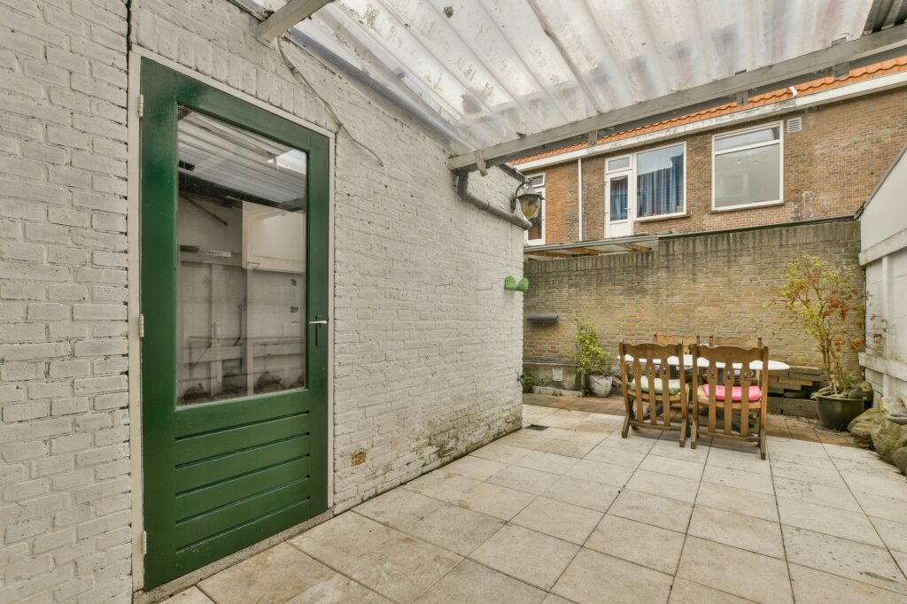 a patio with a green door and a dining table