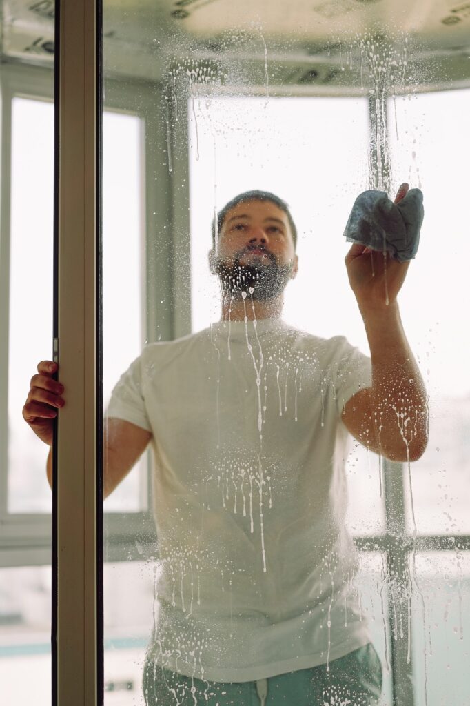 Man washing big glass door at home