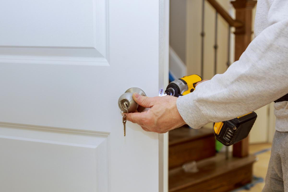 Hands repairing a door lock with a screwdriver