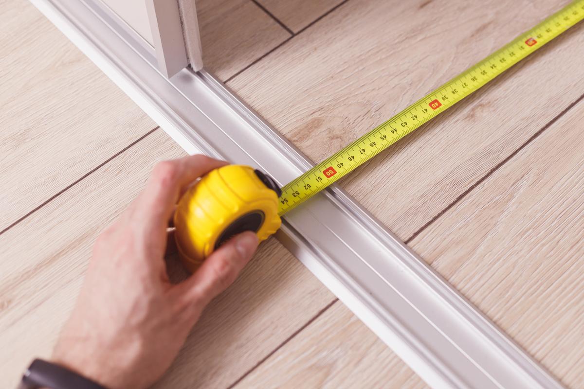 Tape measuring depth of wardrobe from wall to down rails