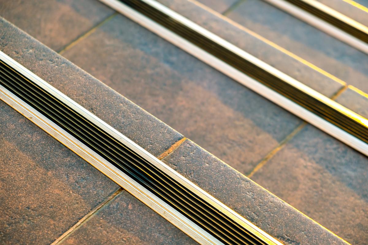 Closeup of ceramic tiles covering porch stairs with rubber anti slippery stripes on it.